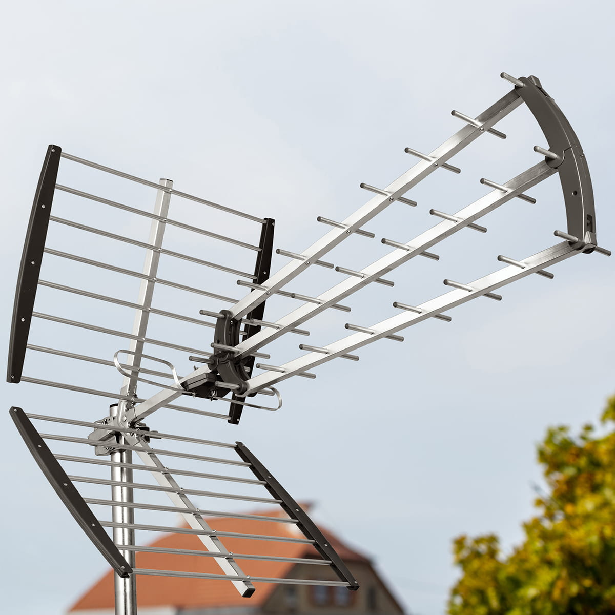 Metalowa antena TV, zamontowana na słupie, na tle pochmurnego nieba.