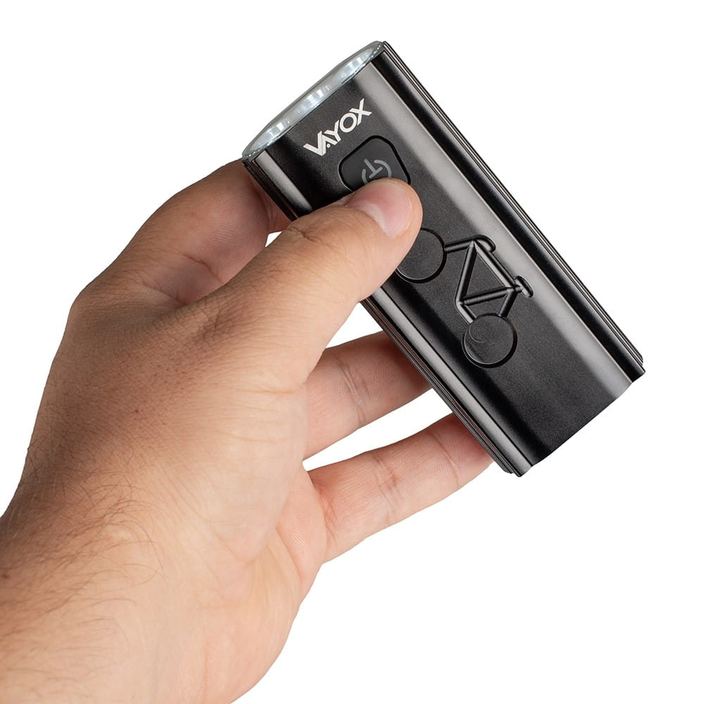 Dłoń trzymająca czarne światło rowerowe z przyciskiem zasilania i symbolem roweru.