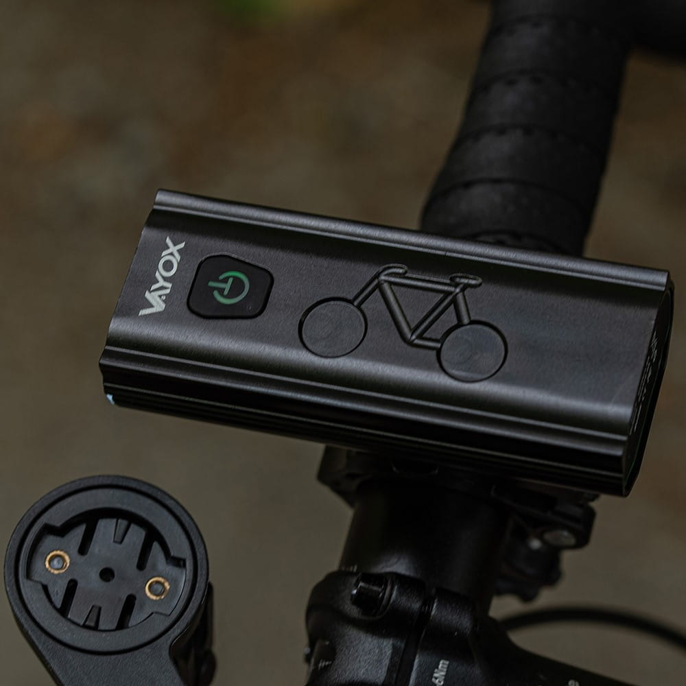 Czarne światło rowerowe na kierownicy. Czarna owijka kierownicy. Zielony przycisk zasilania.