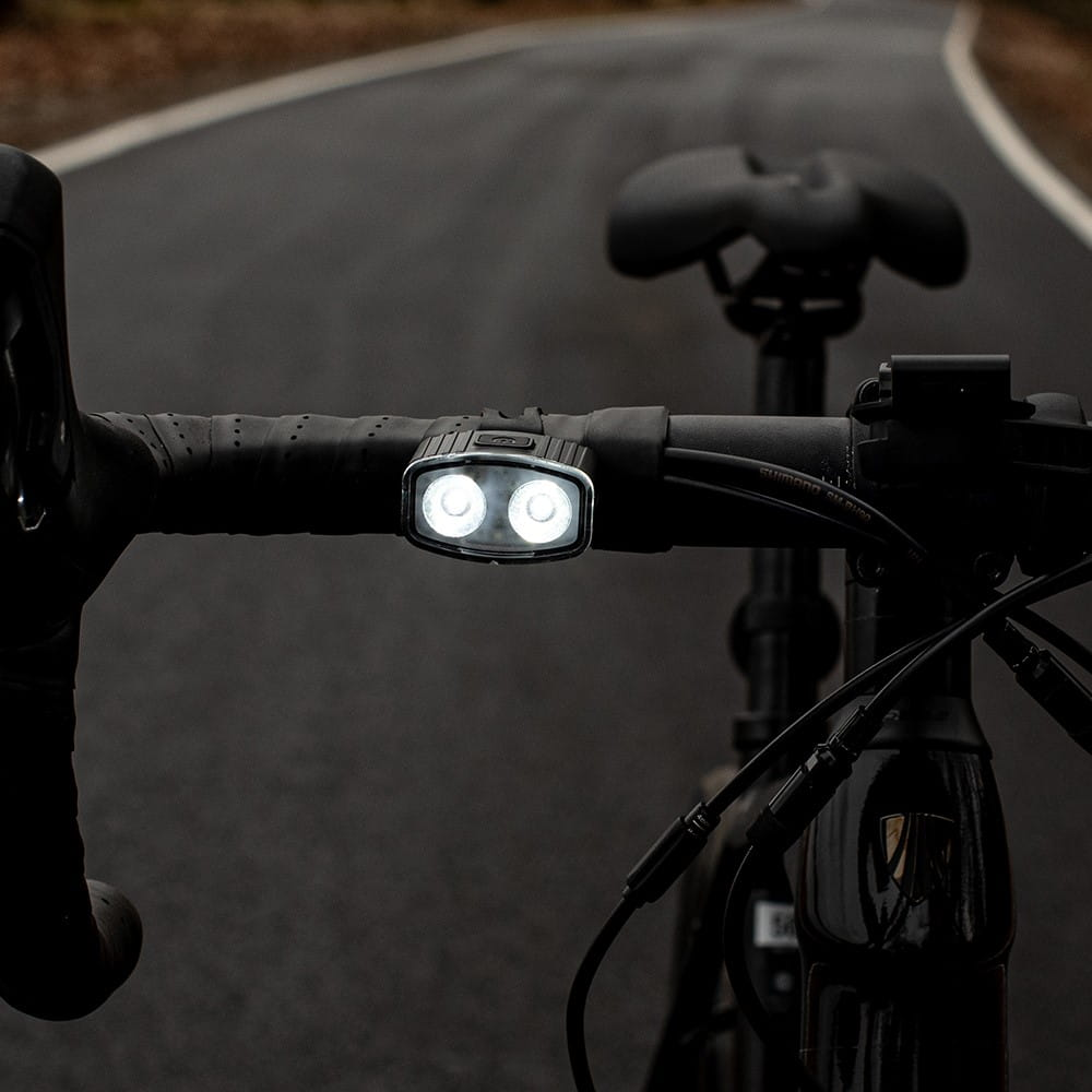 Kierownica roweru ze światłem. Światło jest włączone i ma dwa światła.