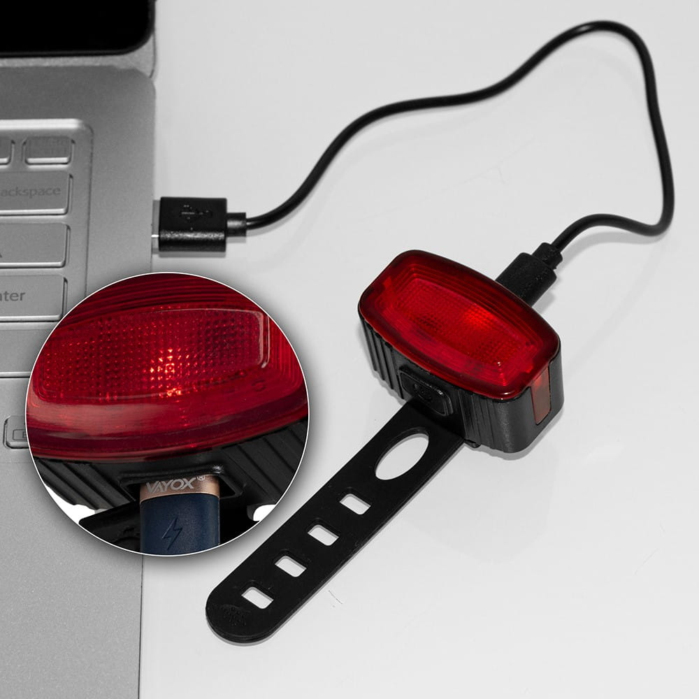 Laptop jest podłączony do czerwonej lampki rowerowej przez USB. Światło jest podłączone i włączone.