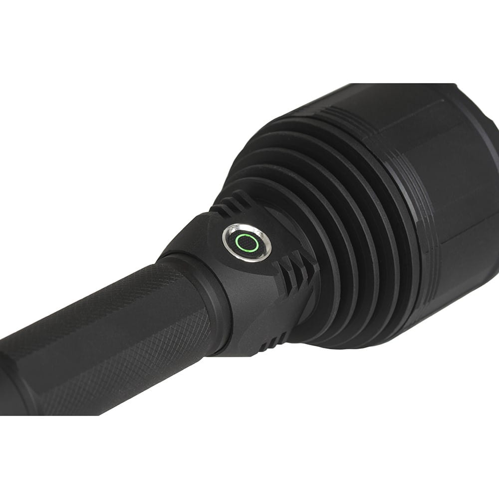 Zbliżenie głowicy czarnej latarki z zielonym przyciskiem zasilania, białe tło.