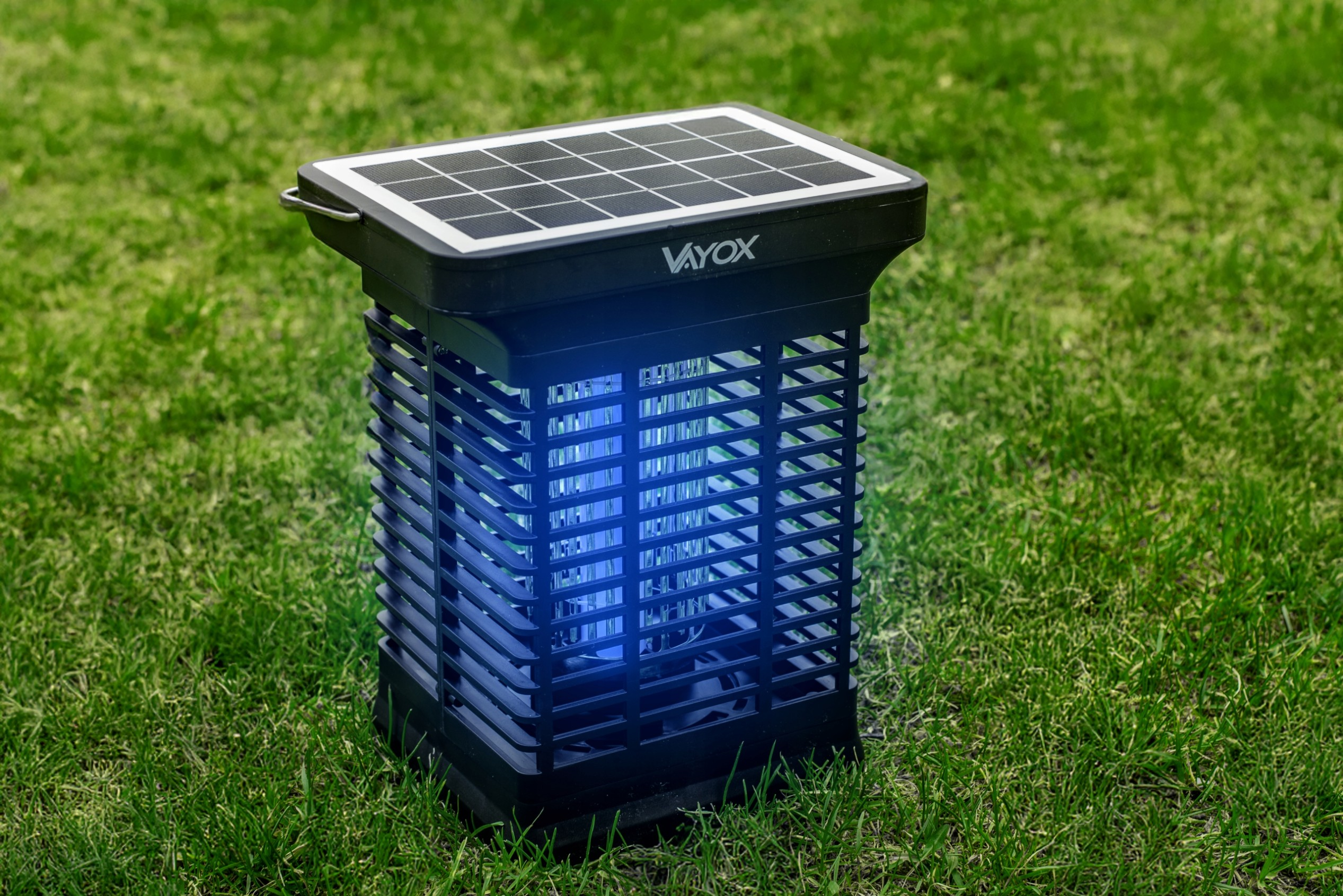 Czarny zabójca owadów na trawie, emitujący niebieskie światło z panelu słonecznego.