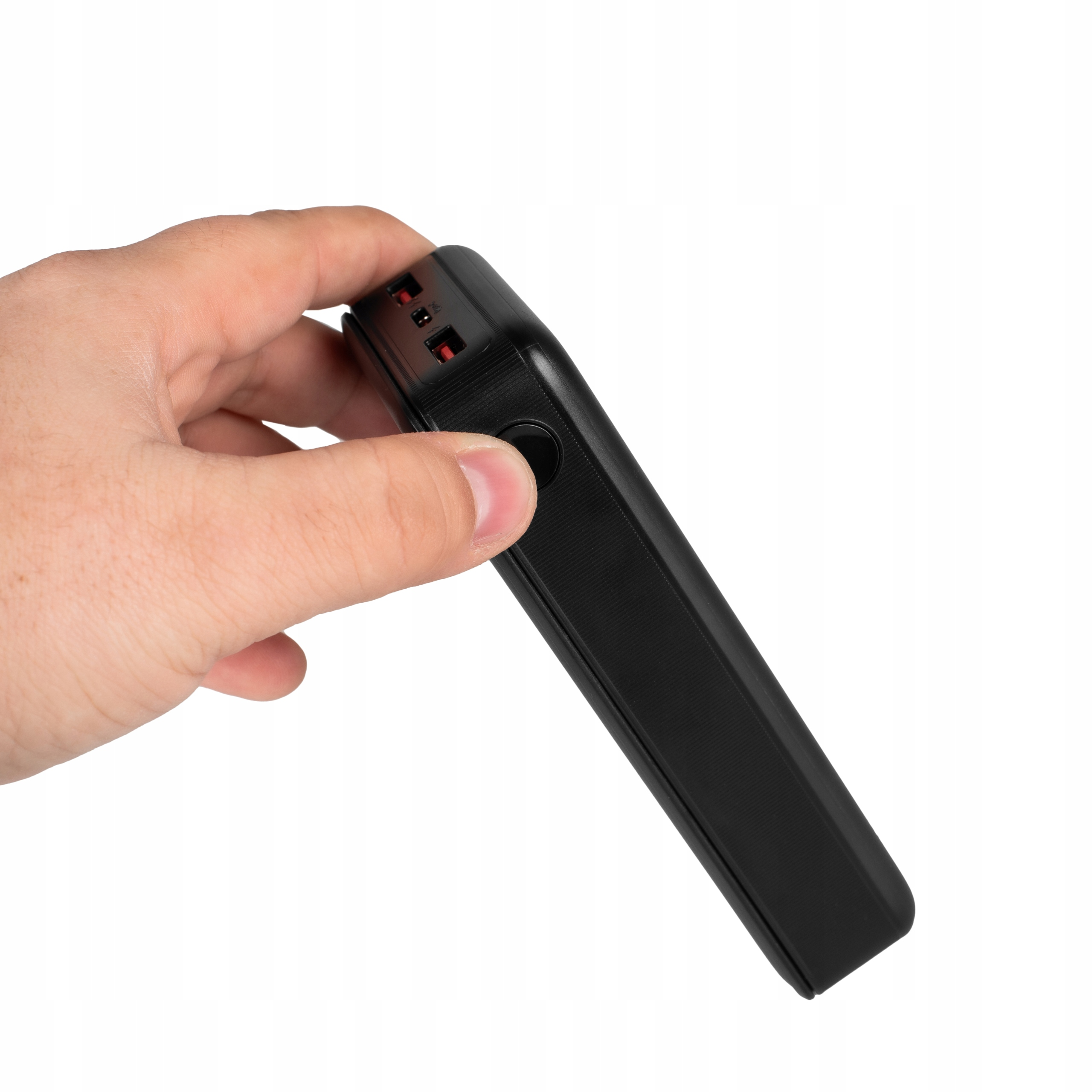 Ręka trzymająca czarne urządzenie z portami zasilania i USB.