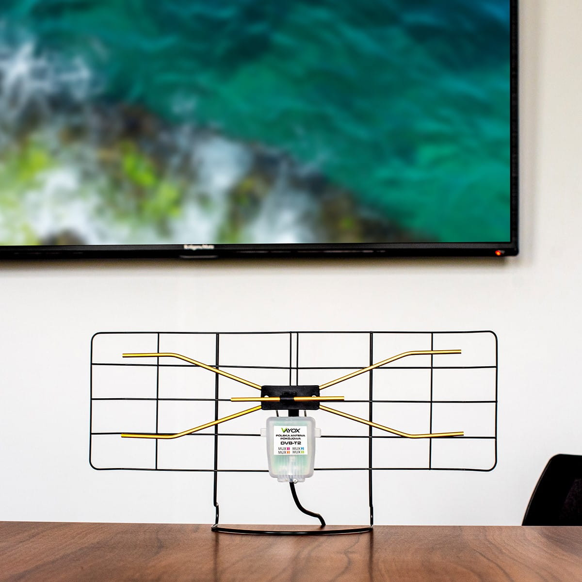 Antena TV na stole przed ekranem telewizora. Czarny i złoty.