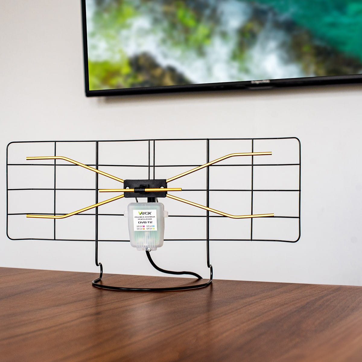 Antena TV na stole. Czarny i złoty. Ekran telewizora w tle.