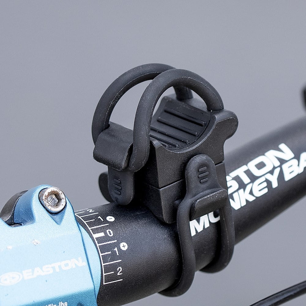 Zbliżenie czarnego uchwytu na światło rowerowe na czarnej kierownicy.