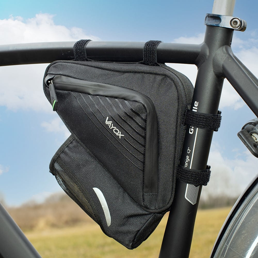 Czarna torba rowerowa przymocowana do ramy roweru. Zielone pole w tle.