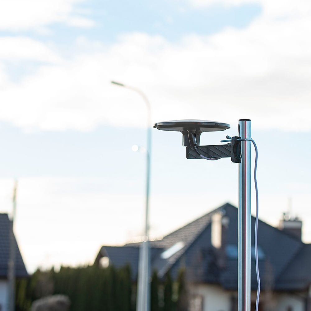 Antena zamontowana na słupie, budynki i niebo w tle.