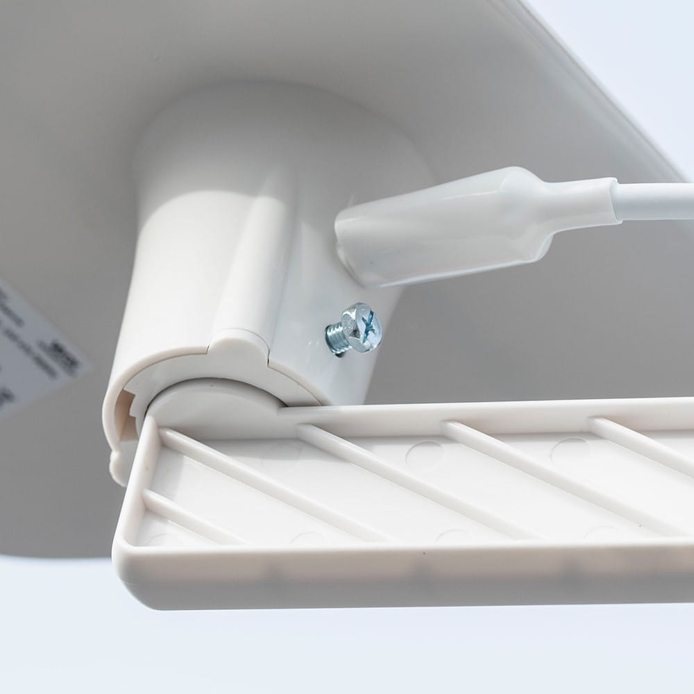 Biała płyta montażowa ze śrubą i białą, kątową częścią ze szczelinami na urządzenie.