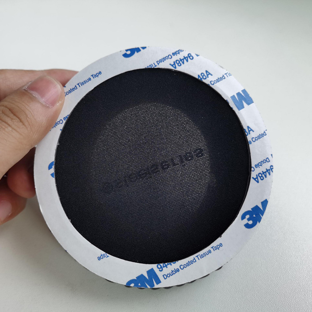 Runder schwarzer Mesh mit weißem Klebeband. Das Band hat Text. Isoliert auf Weiß.
