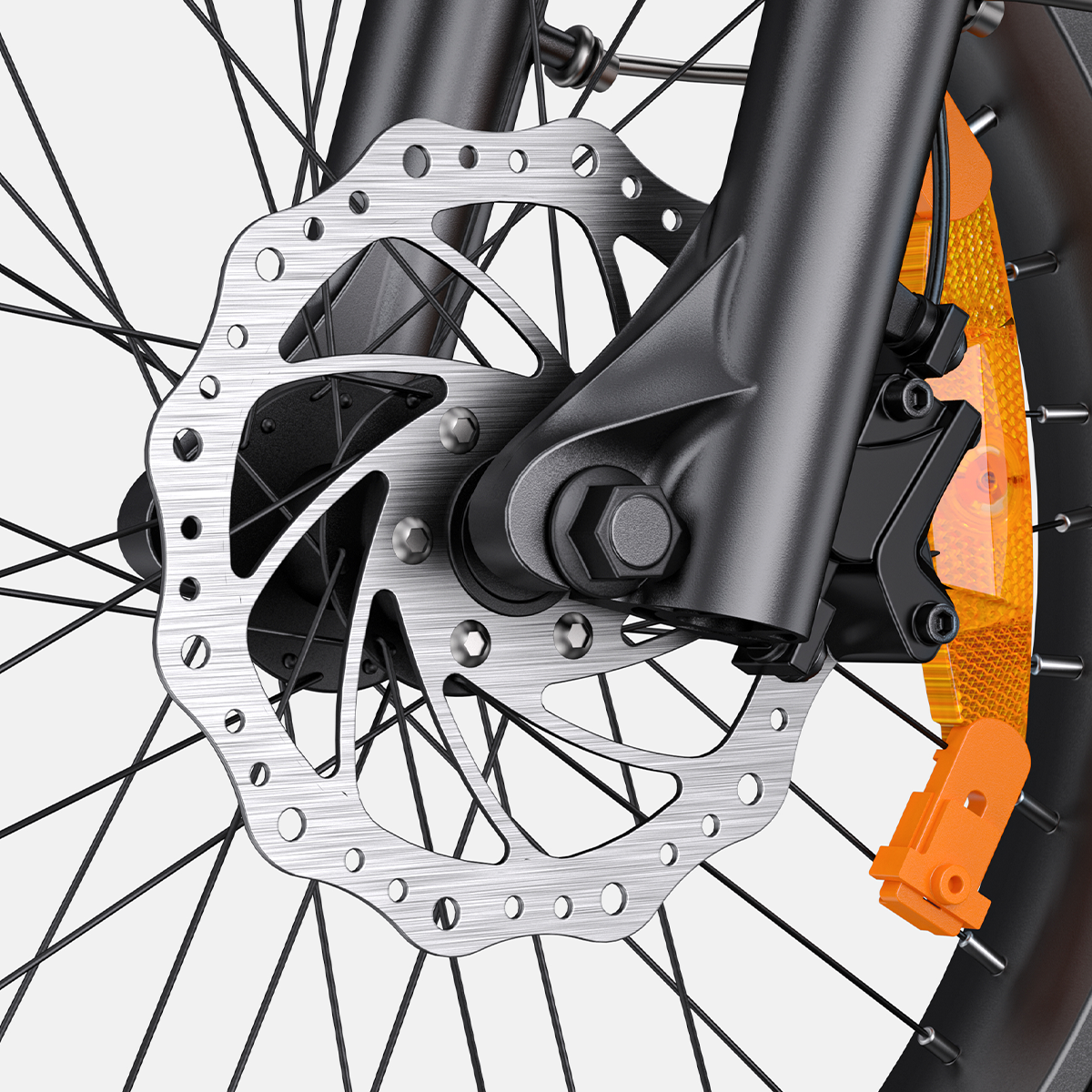 Zbliżenie koła roweru z hamulcem tarczowym. Srebrzysta tarcza z otworami, czarne szprychy, pomarańczowy pasek.