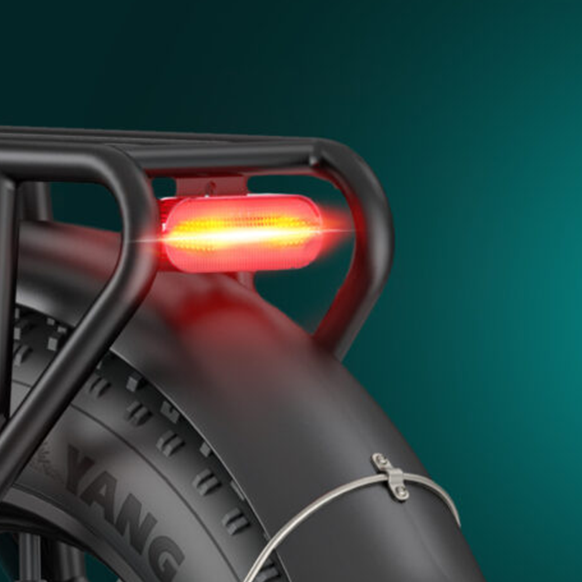Zbliżenie tylnego światła roweru, kolor czerwony, opona widoczna w tle.
