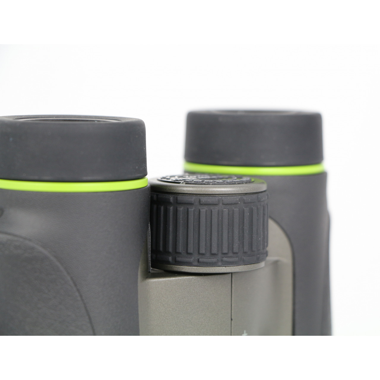 Zbliżenie lornetki. Czarna z zielonymi akcentami. Pokrętło ostrości pośrodku.