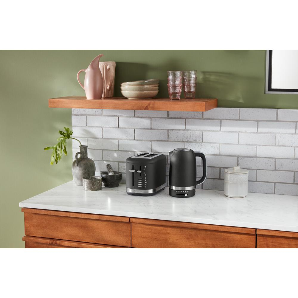 Black toaster and kettle on a marble countertop.  Shelves on the top.  White brick wall.