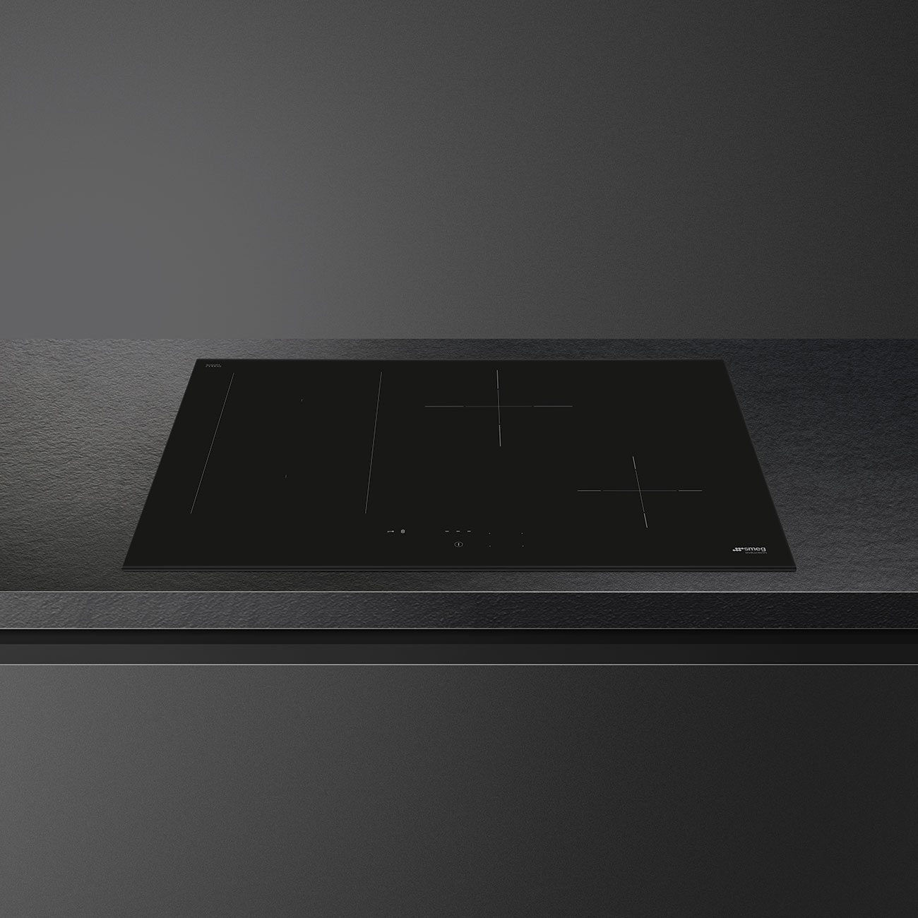 Piano cottura a induzione nero con quattro zone, su piano scuro.