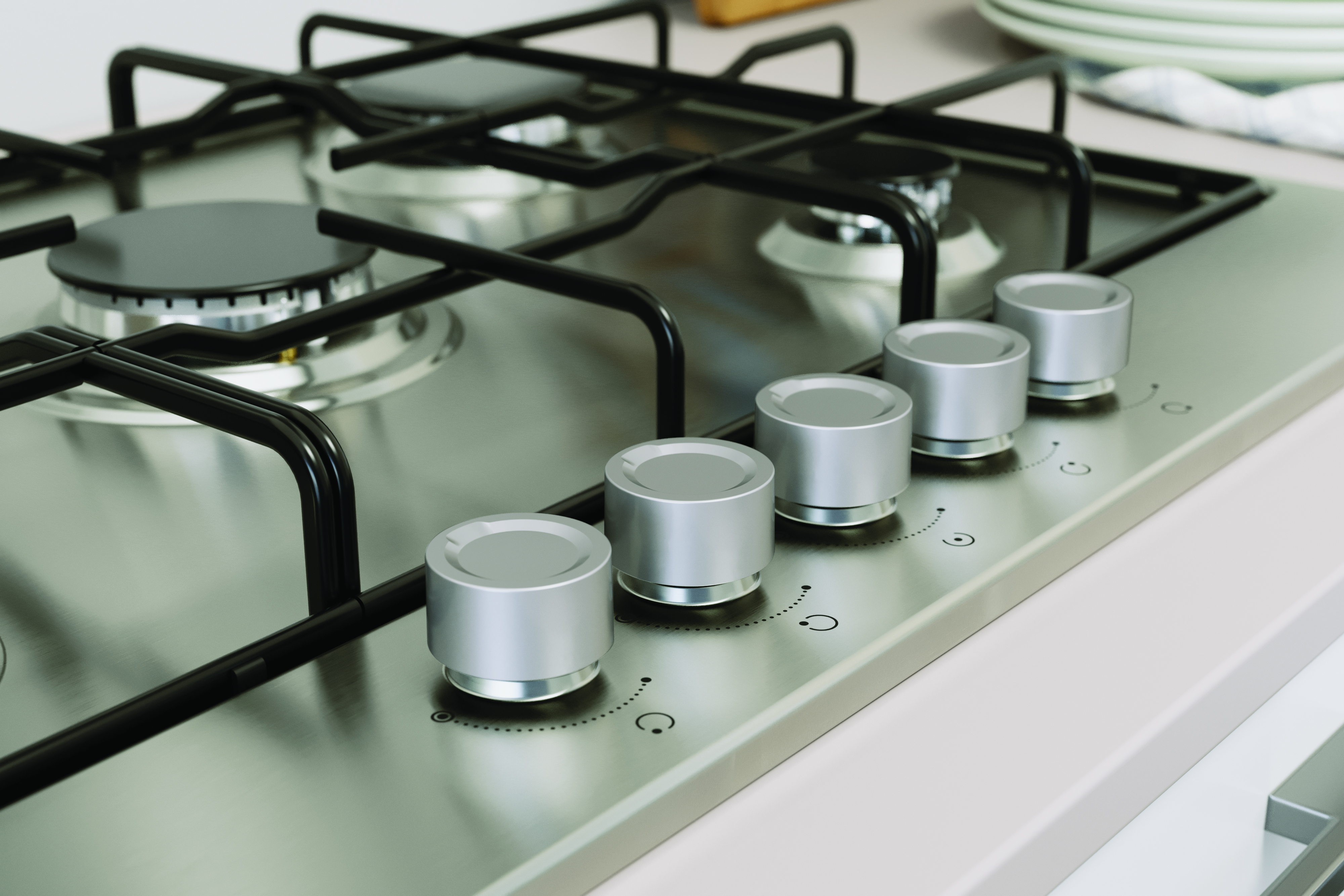 Zbliżenie gazowej płyty kuchennej ze stali nierdzewnej z pokrętłami i otoczeniem kuchni.