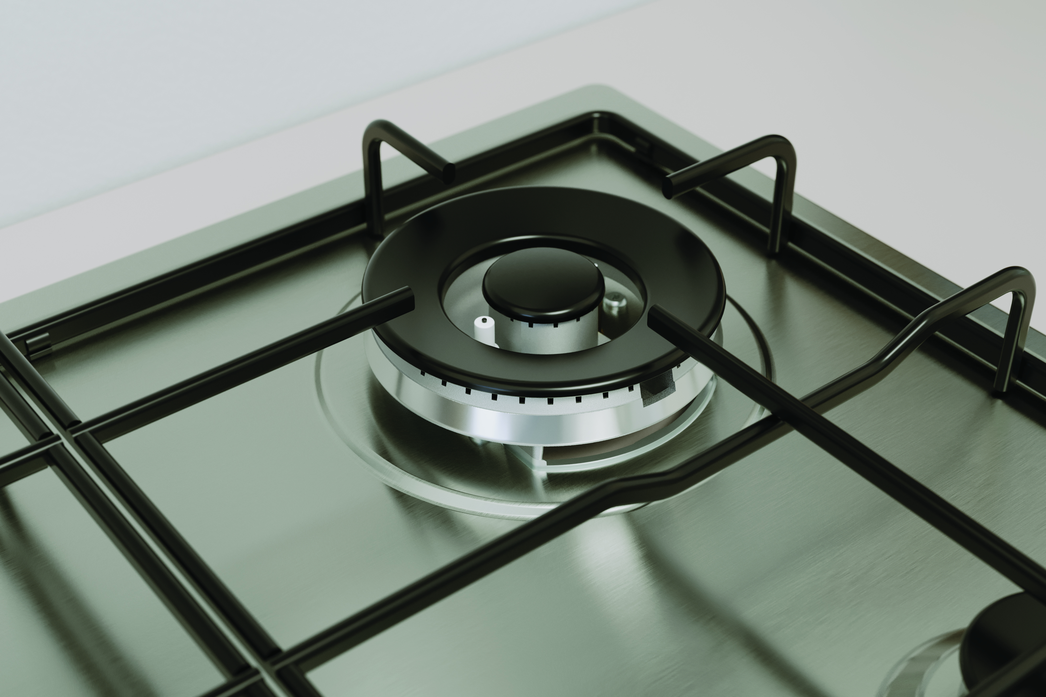 Zbliżenie palnika gazowego na płycie ze stali nierdzewnej. Ma czarny ruszt i czarną nasadkę palnika.