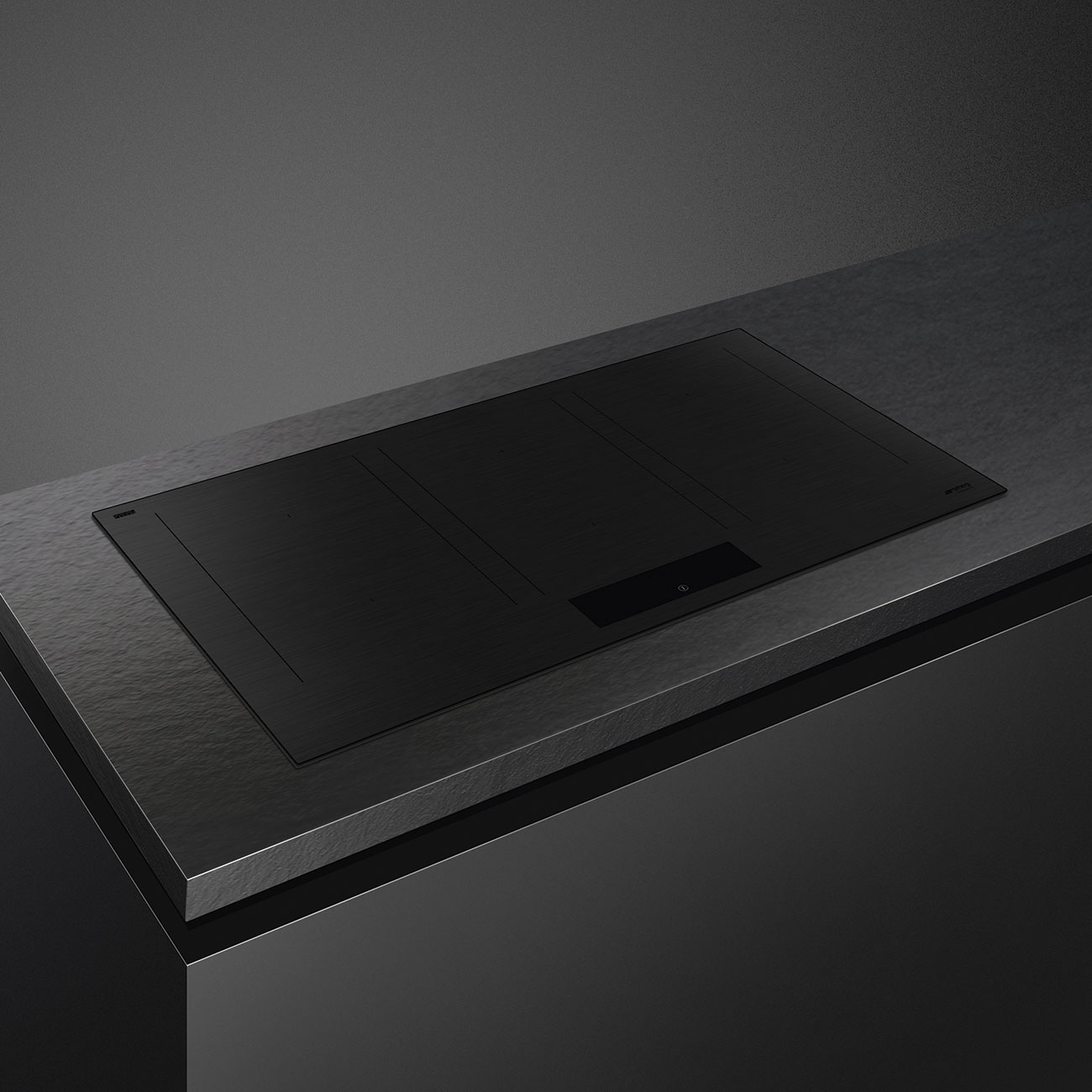 Piano cottura nero incassato su un piano di lavoro scuro. Ha tre zone e un pannello touch.