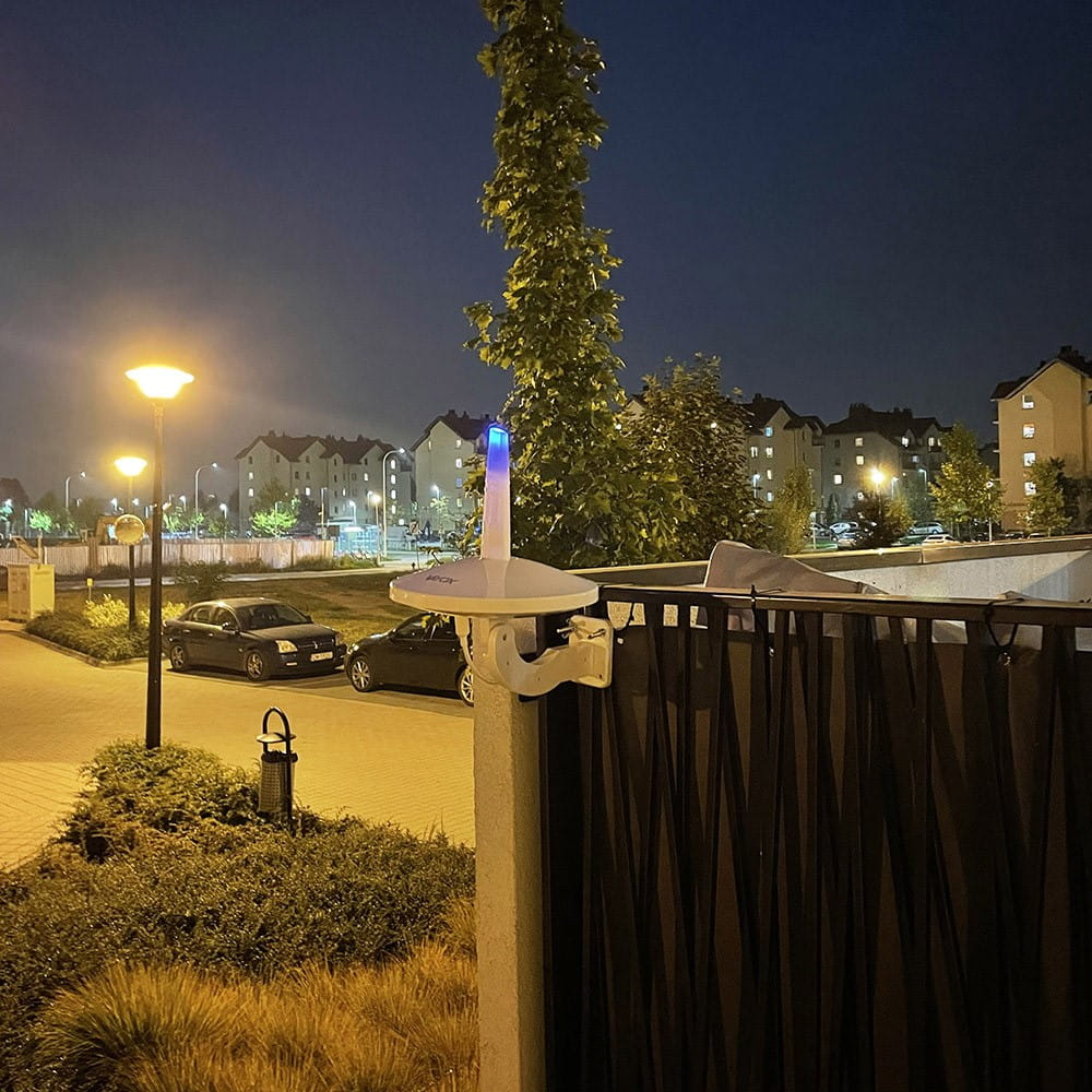 Antena na ścianie w nocy. Światła miasta w tle.