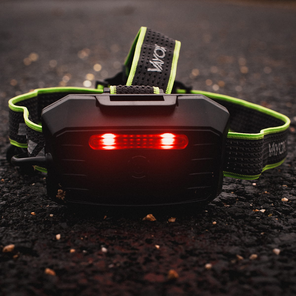 Latarka czołowa na ciemnej powierzchni. Czerwone światła na latarce czołowej.