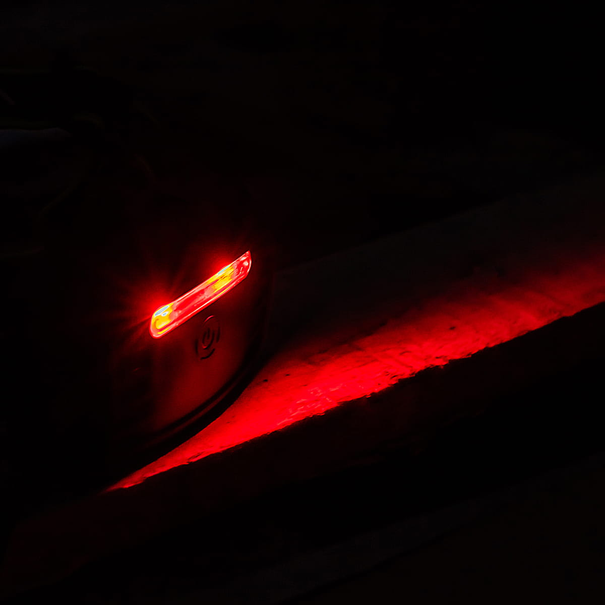 Ciemne zdjęcie. Czerwone światło z latarki oświetla powierzchnię.