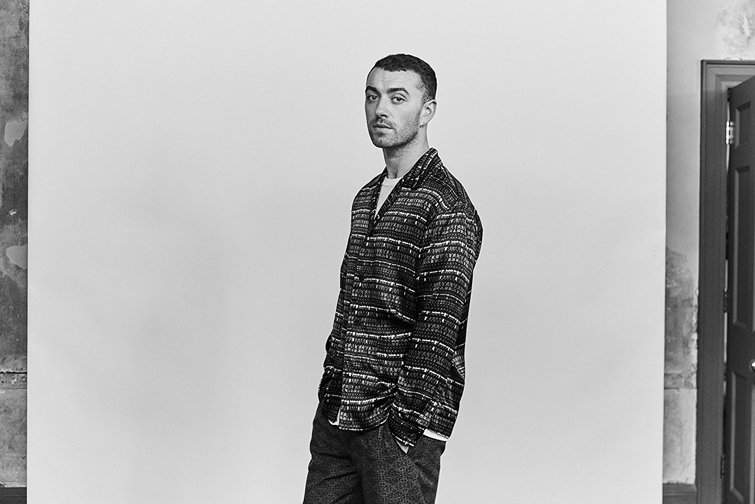 Sam Smith con una camicia fantasia, posa in bianco e nero.