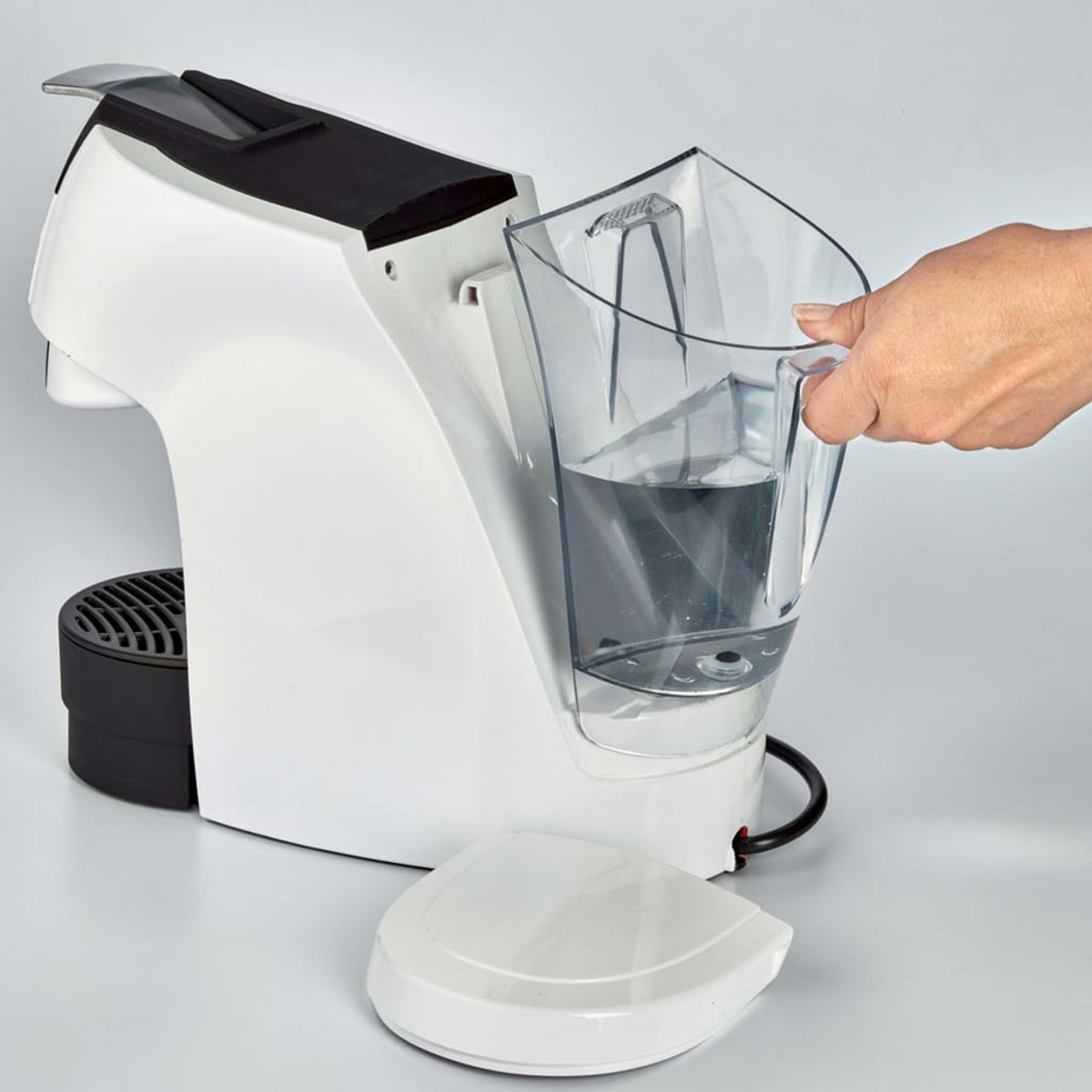 Biało-czarny ekspres do kawy, do którego wlewa się wodę.