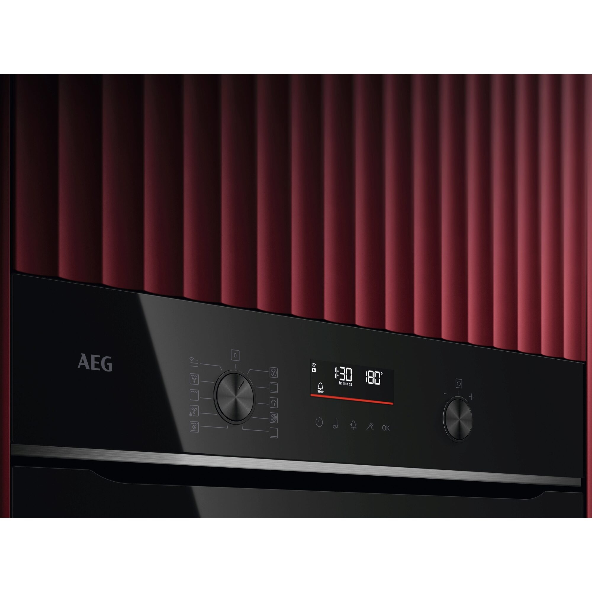 Pannello comandi forno nero con display digitale e manopole. Sfondo rosso strutturato.