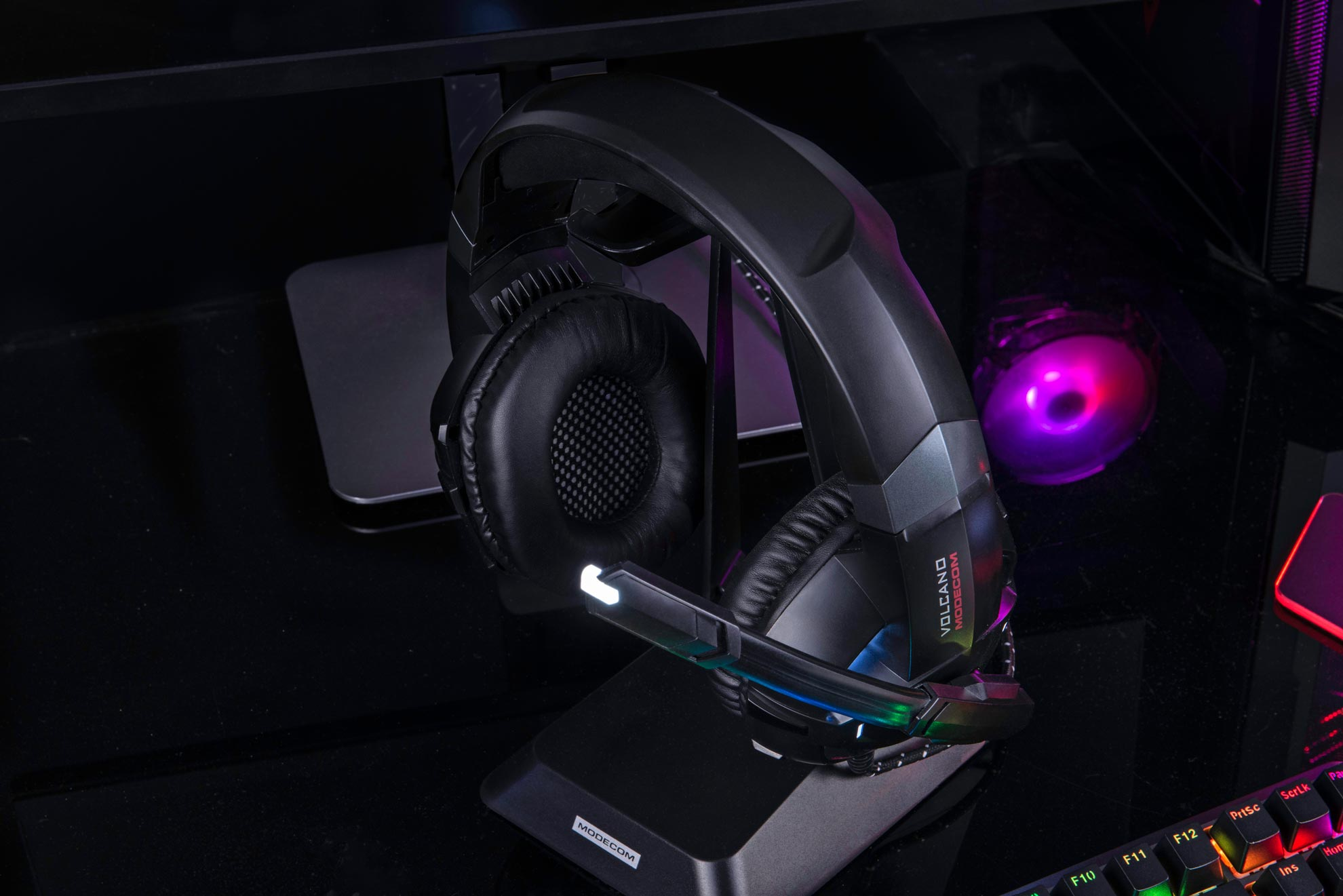 Czarne i czerwone słuchawki dla graczy na stojaku. Monitor i światło w tle.