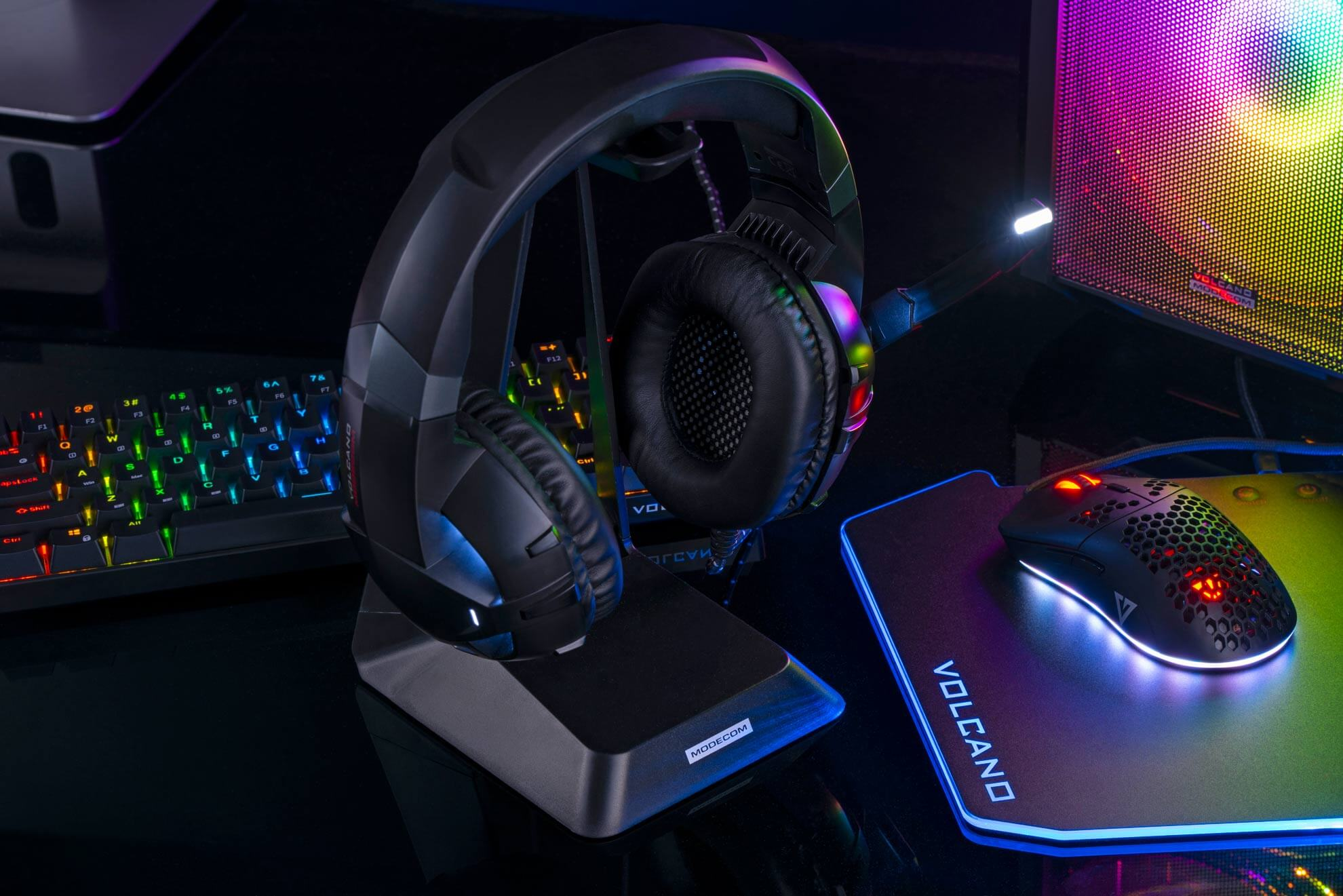 Zestaw słuchawkowy dla graczy na stojaku. Klawiatura i mysz w tle, wszystko podświetlone.