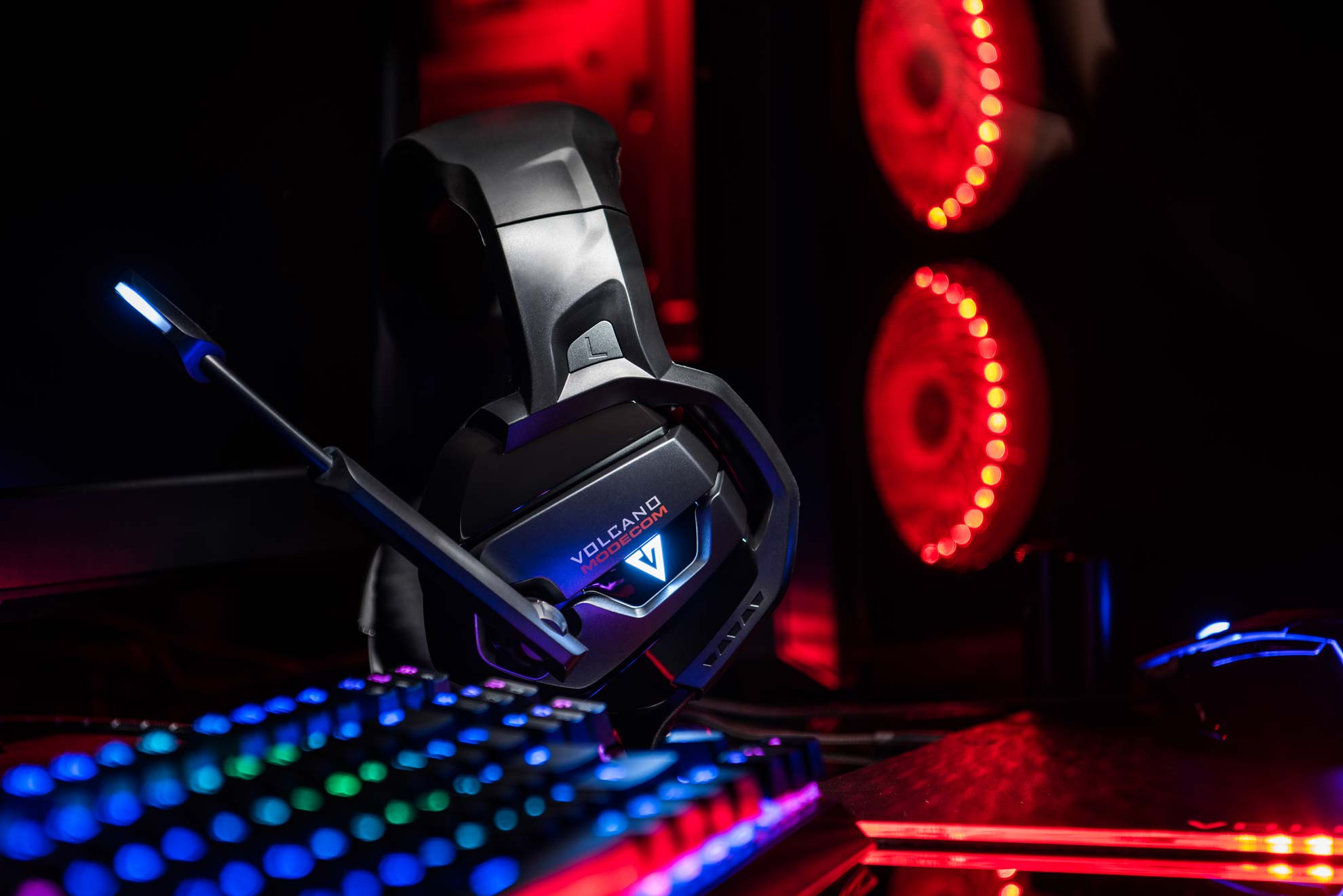 Czarny zestaw słuchawkowy dla graczy z mikrofonem, klawiaturą i komputerem w tle.