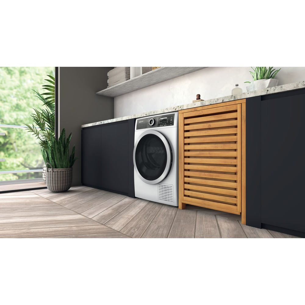 Eine Waschmaschine in einem Waschraum. Rechts befindet sich ein Holzschrank.