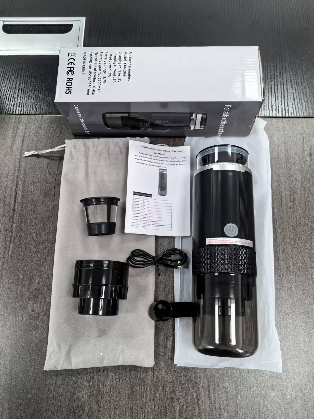 Zerlegter tragbarer Kaffeebereiter mit Schachtel, Filter, Tasse und Anleitung auf Holzoberfläche.