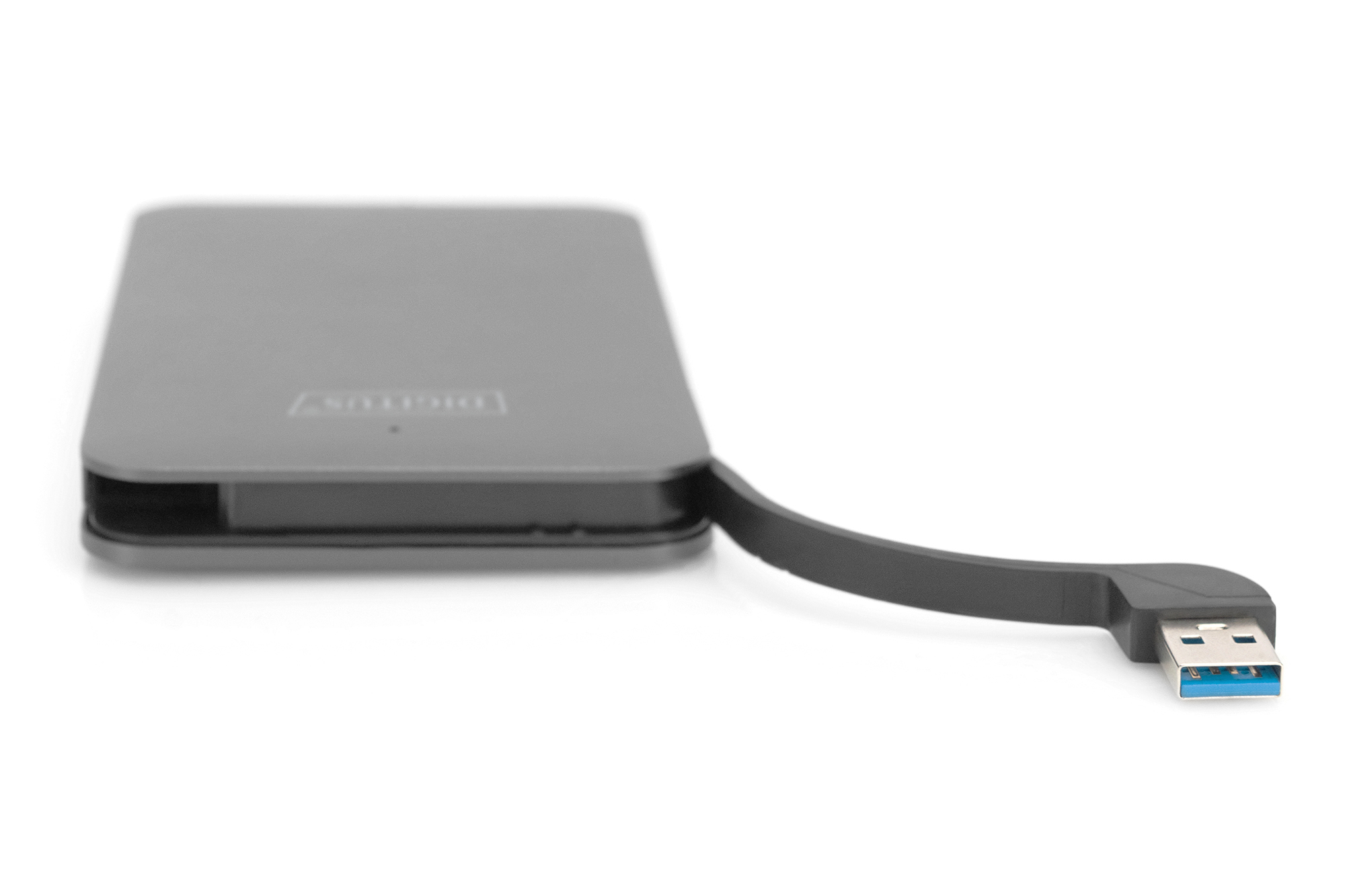 Szary zewnętrzny dysk twardy z podłączonym kablem USB, leżący na białej powierzchni.