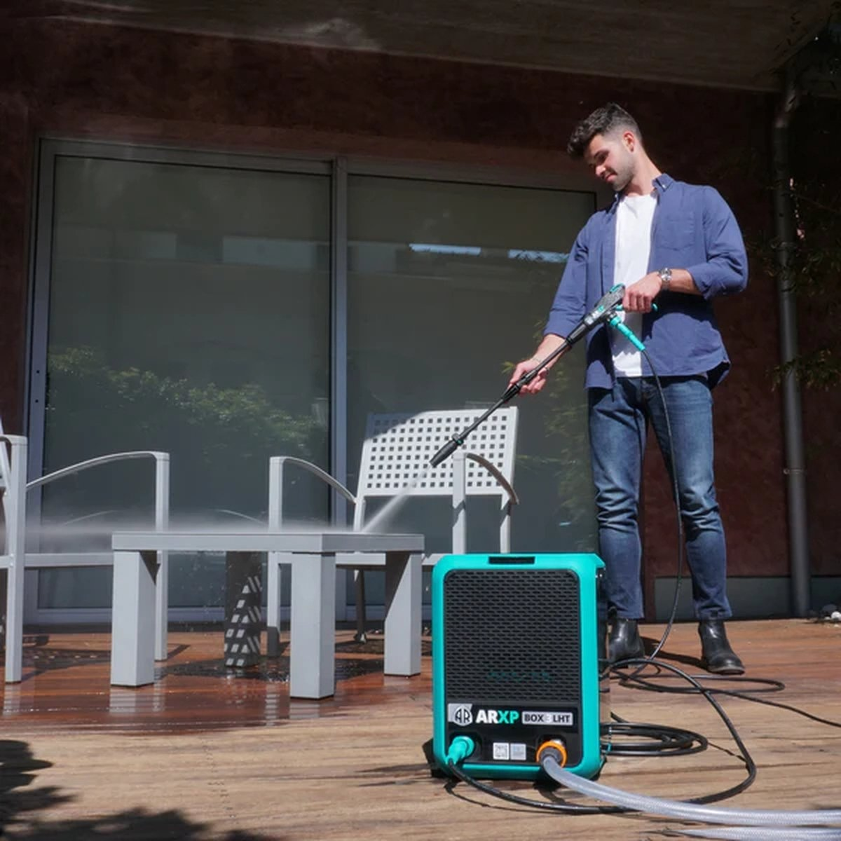 Un uomo sta lavando una casa con un'idropulitrice ARXP BOX 3 LHT color verde acqua.
