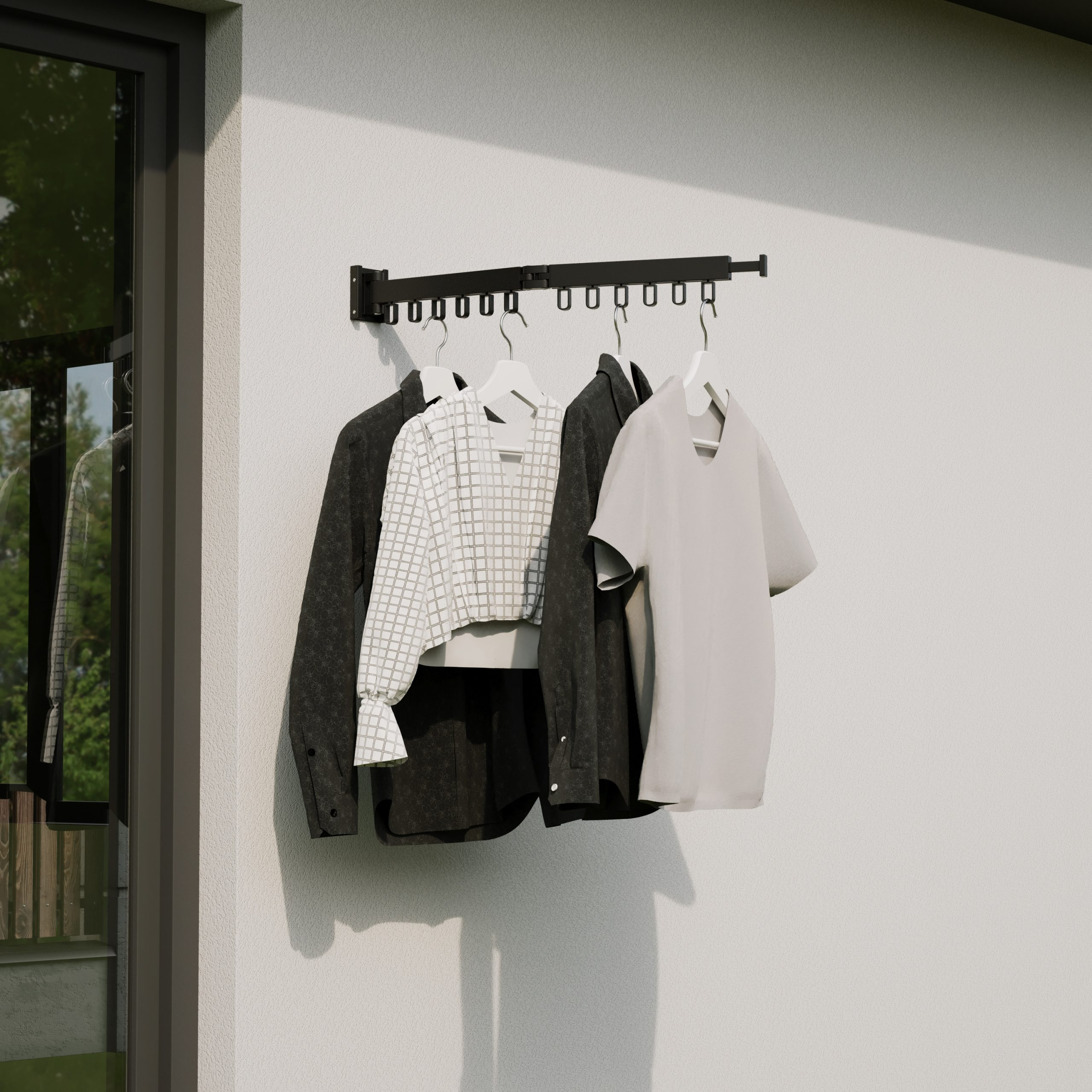 Vêtements suspendus sur un support mural noir à l'extérieur, contre un mur blanc. Comprend des chemises et des vestes.