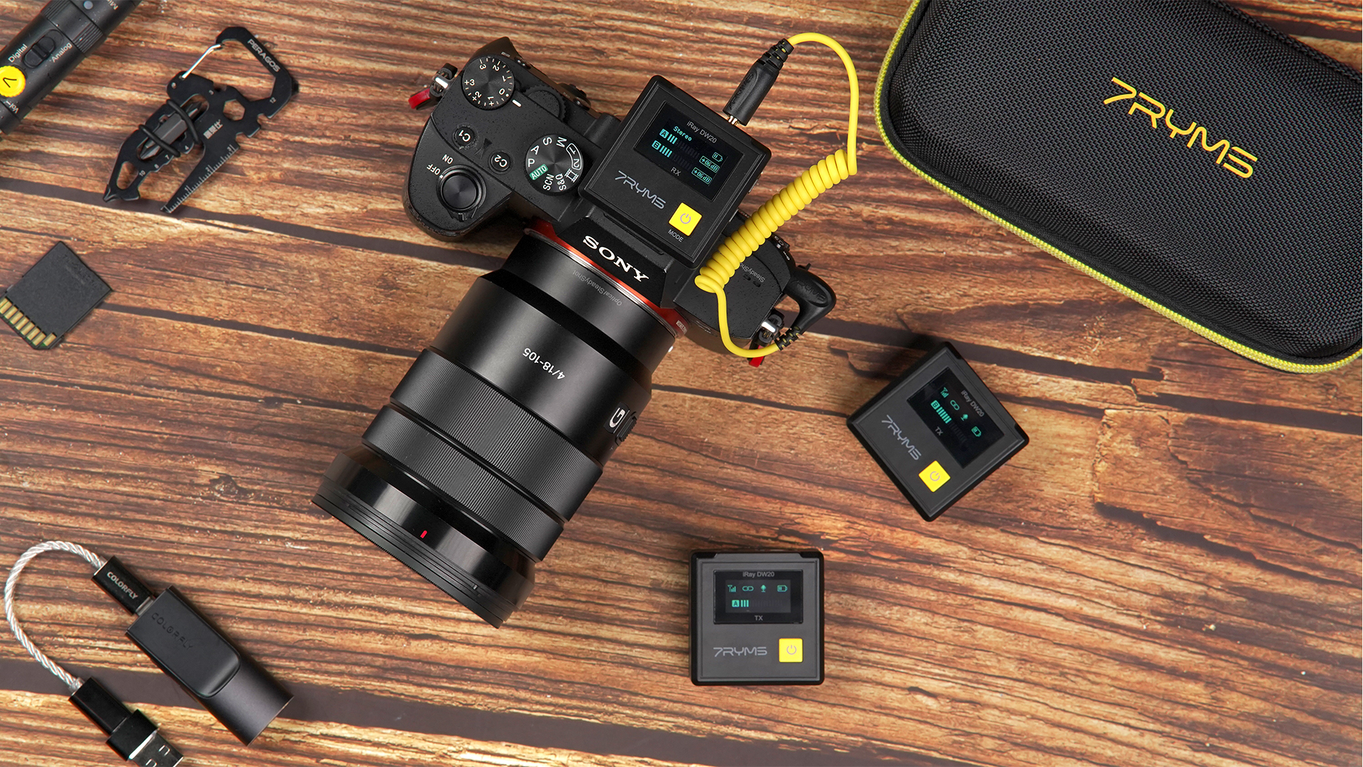 Camera-uitrusting op een houten oppervlak: camera, microfoons en bijbehorende accessoires.