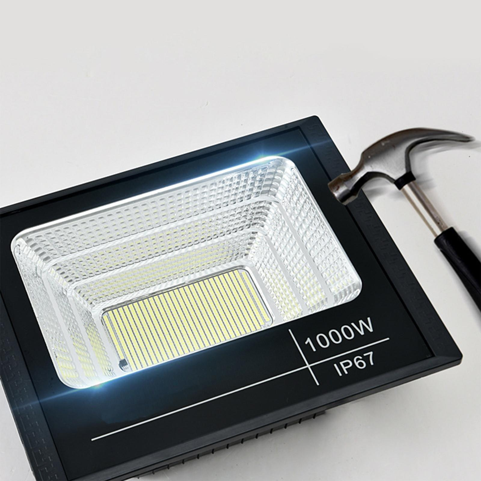 Schwarzer LED-Flutlichtstrahler, 1000W, IP67. Ein Hammer wird daneben gehalten, was Stoßfestigkeit suggeriert.