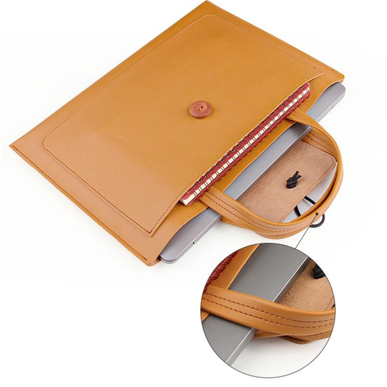Laptop in einer braunen Ledertasche mit Griff. Ein kleines Notizbuch in der Tasche.