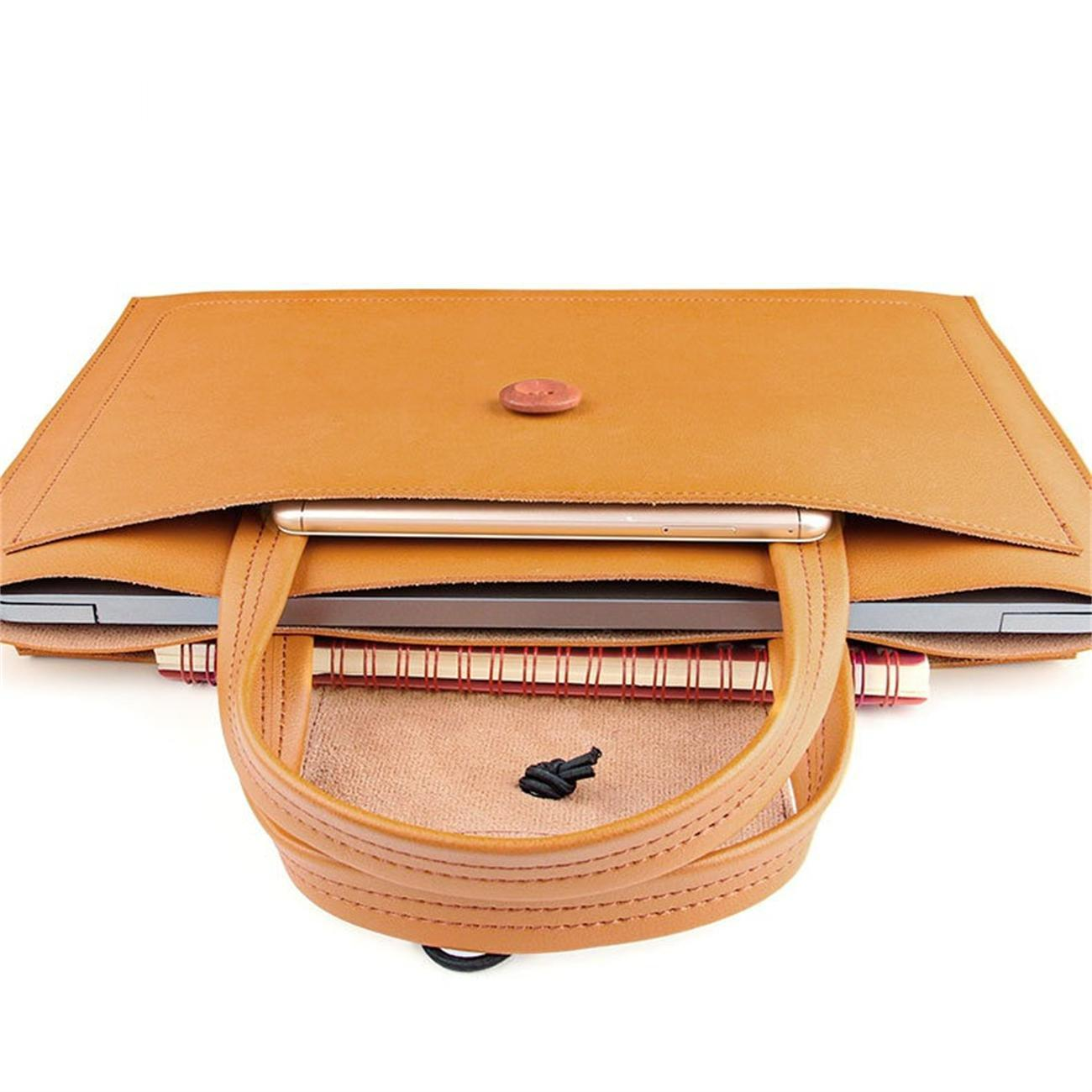 Offene braune Leder-Laptoptasche. Enthält Laptop, Telefon, Notizbuch und ein kleines schwarzes Objekt.