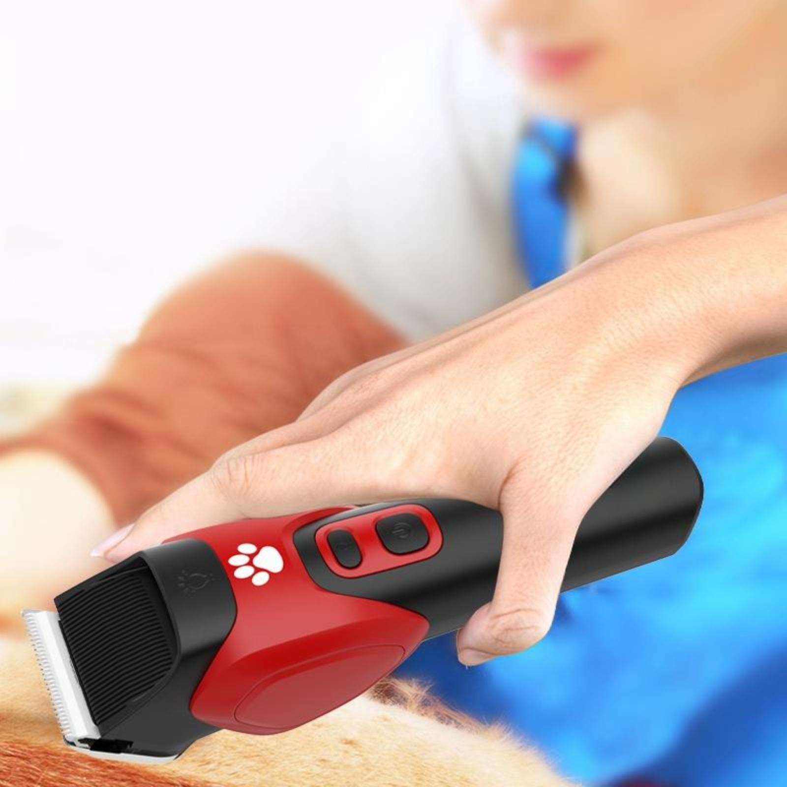 Person verwendet einen rot-schwarzen Haarschneider für Haustiere. Der Trimmer hat ein Pfotenabdrucksymbol.