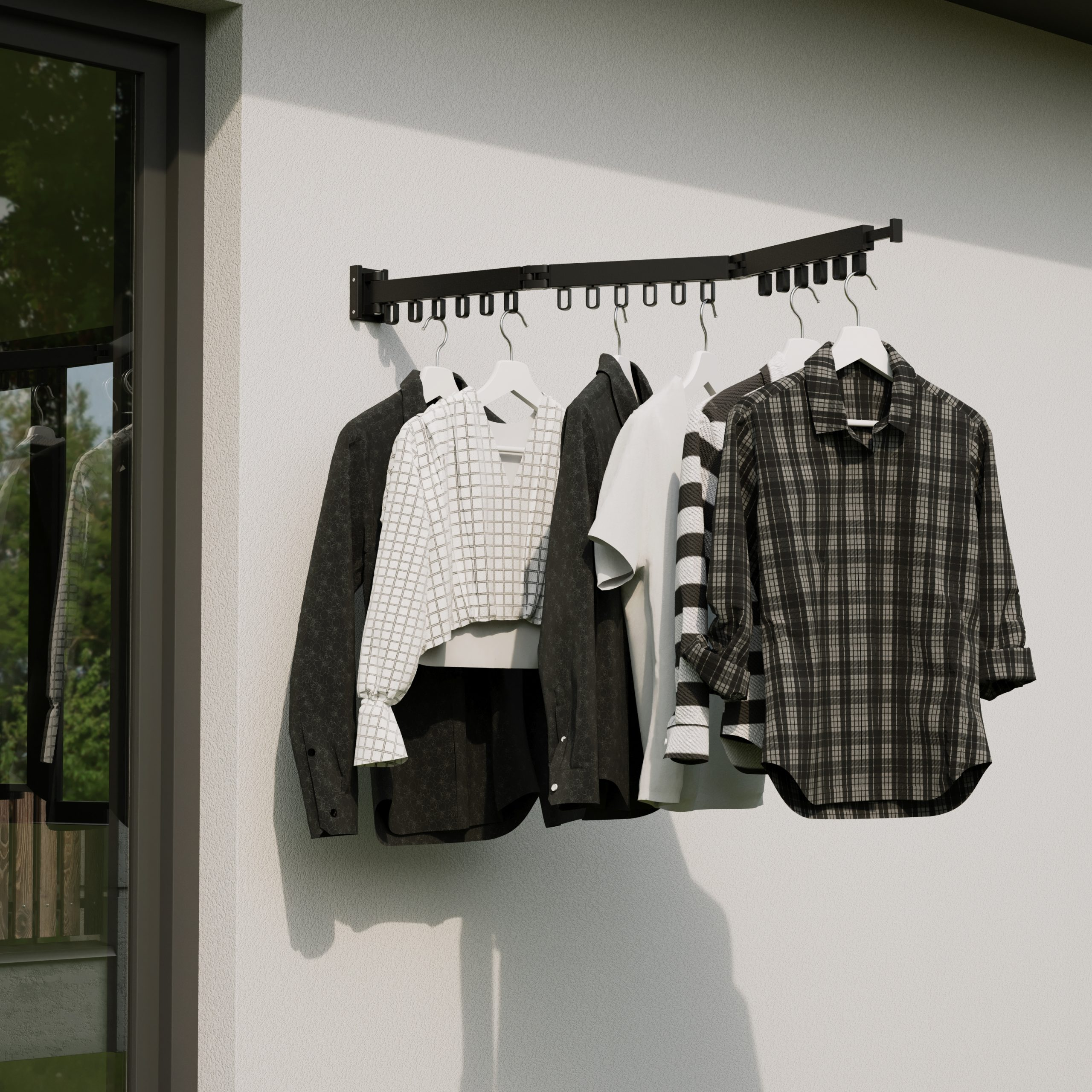 Clothes hanging on a black rack on a white wall.