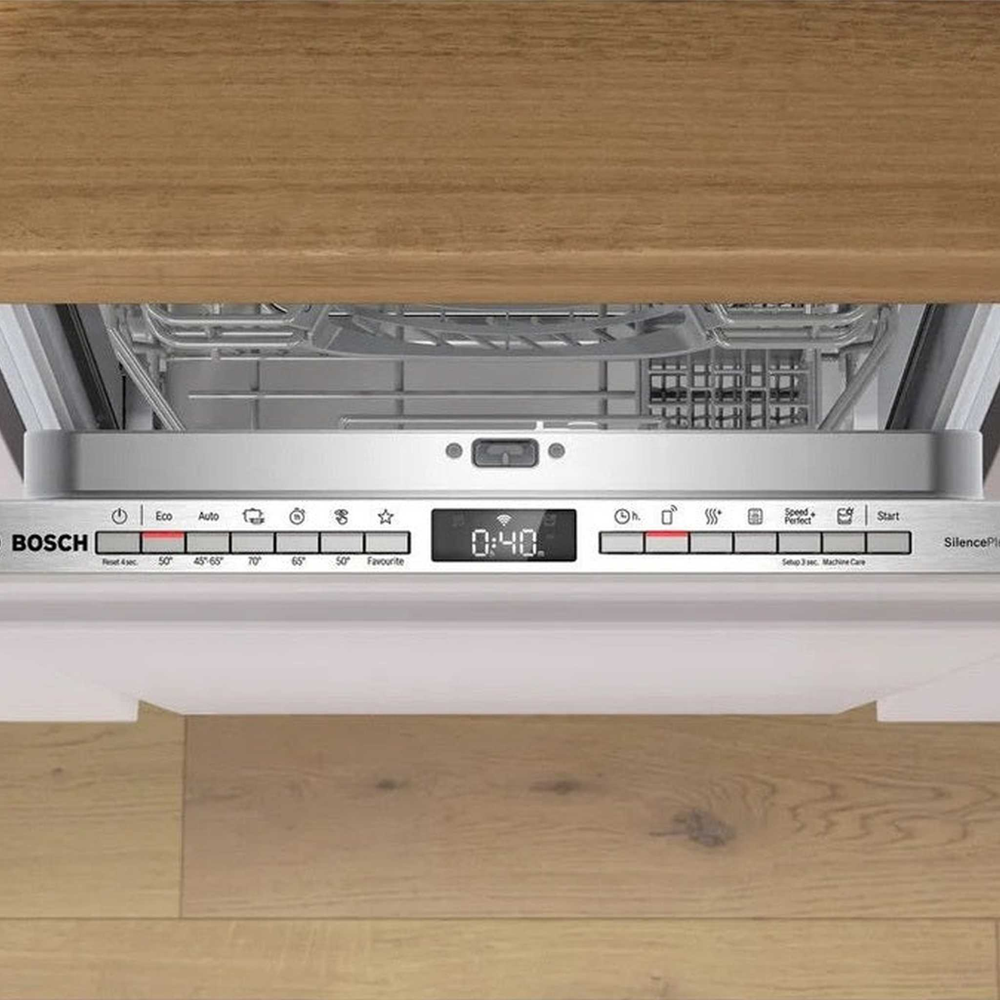 Un pannello di controllo bianco della lavastoviglie con display digitale, sotto un mobile in legno.