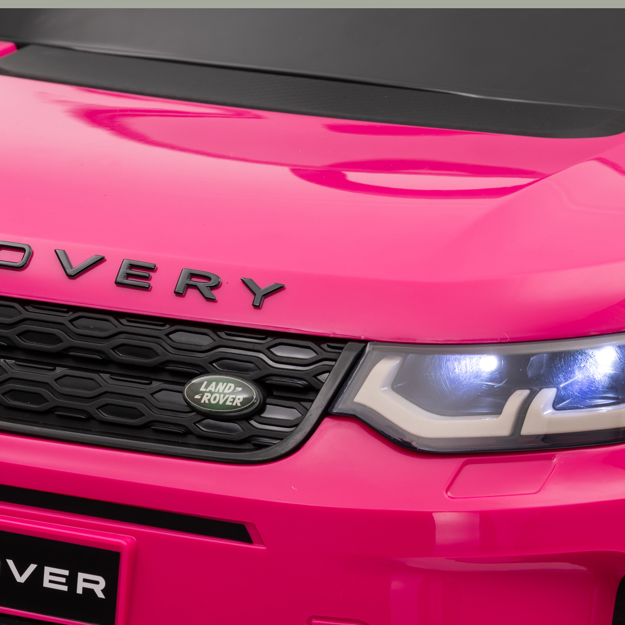 Una vista de cerca del capó rosa y los faros de un coche de juguete.