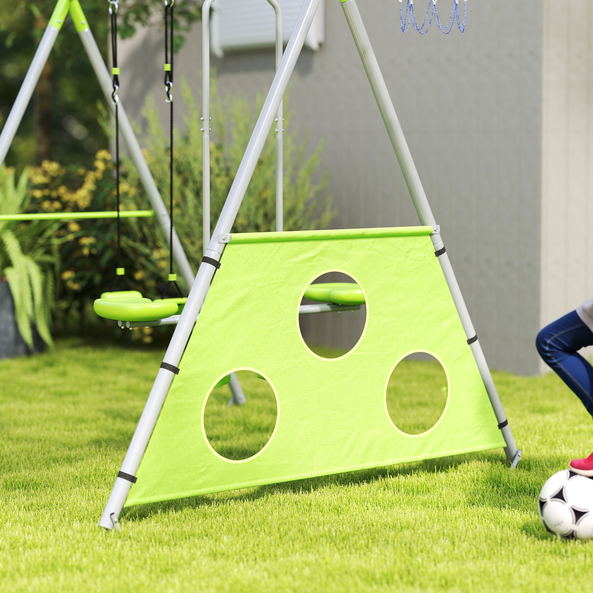 Set de juegos verde con columpio y balón de fútbol en la hierba.