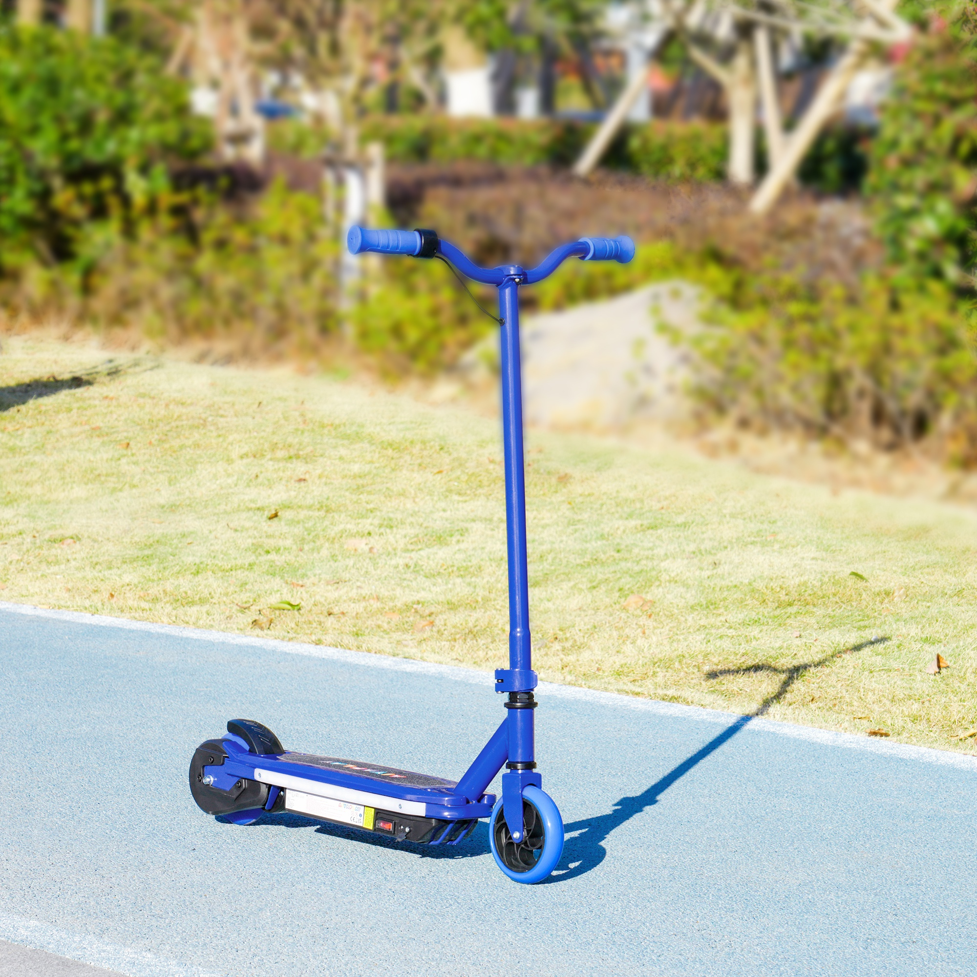 Scooter azul en un camino azul, con hierba verde y árboles borrosos al fondo.