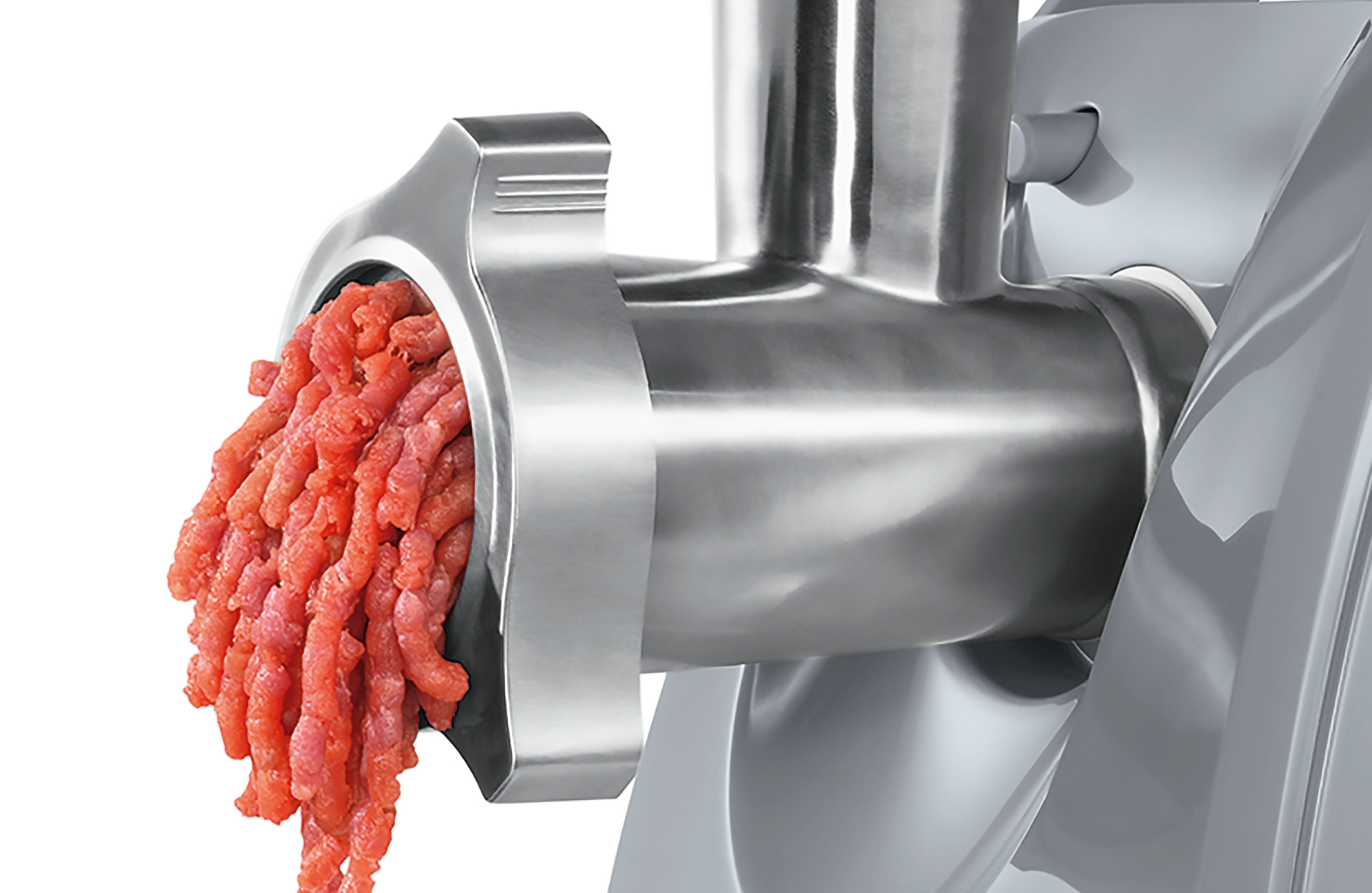 Maszynka do mięsa z wychodzącym mielonym czerwonym mięsem. Maszyna jest srebrna, tło białe.