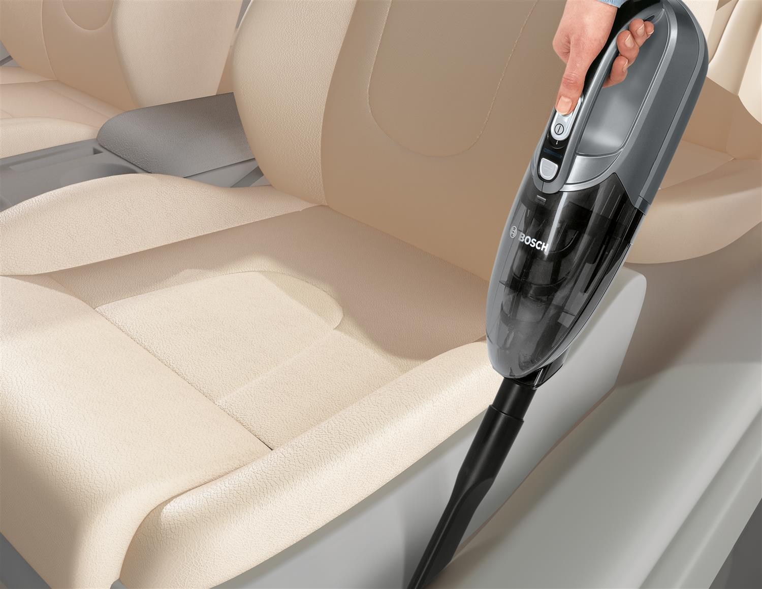Aspiradora de mano limpiando un asiento de coche. Dispositivo negro y gris.