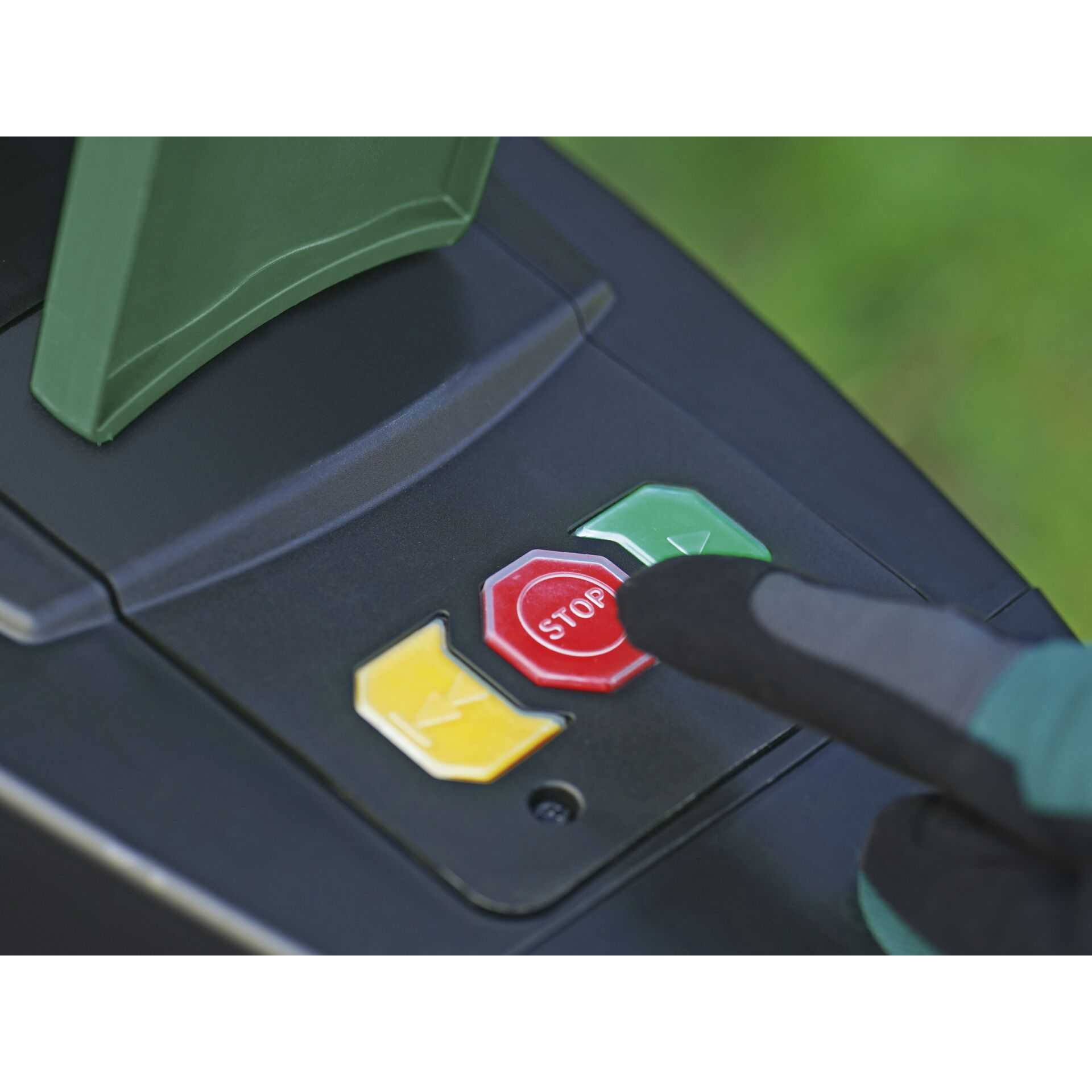 Un doigt ganté appuie sur un bouton rouge d'arrêt sur une machine noire.